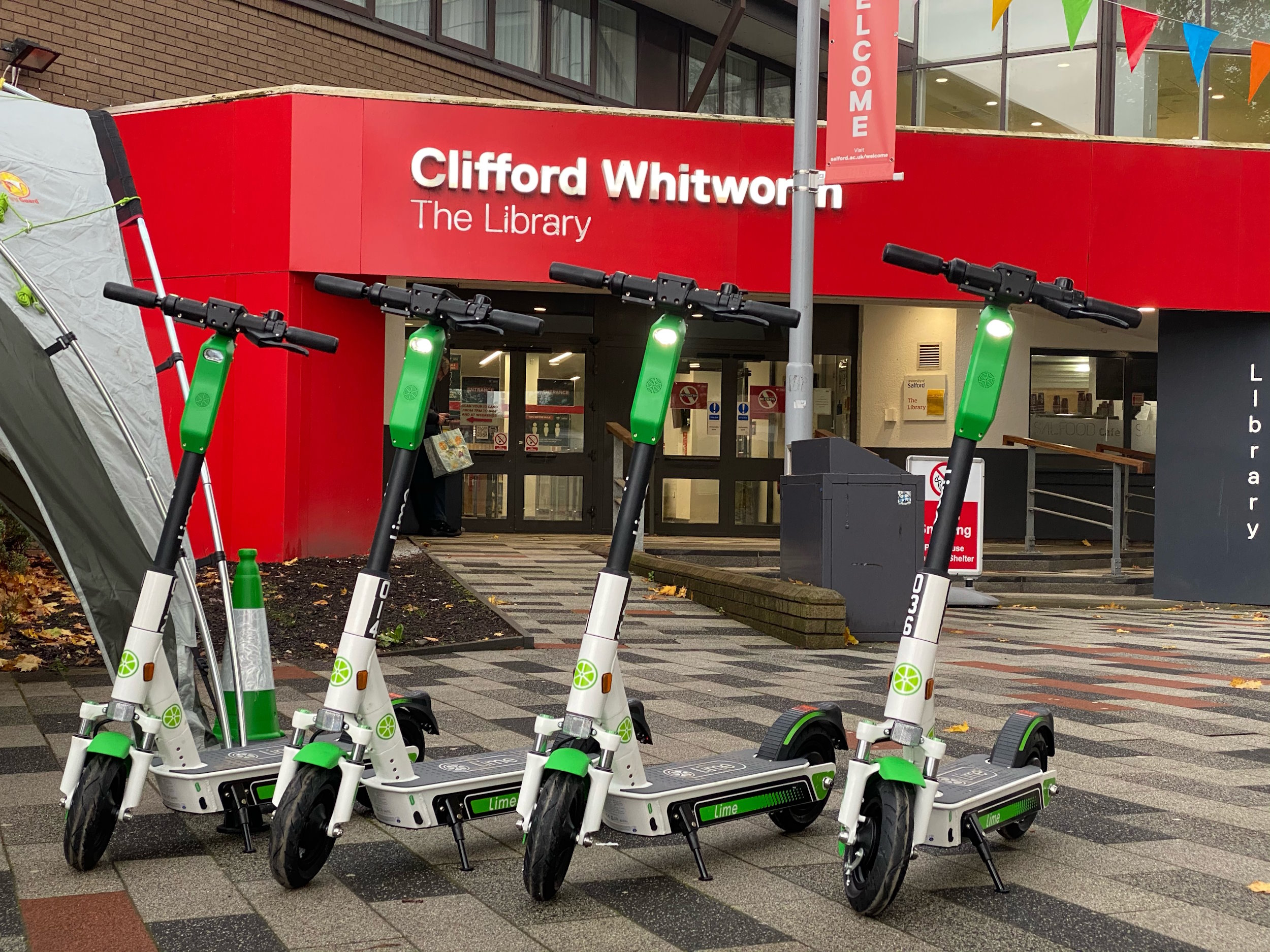 Four e-scooters outside of a library